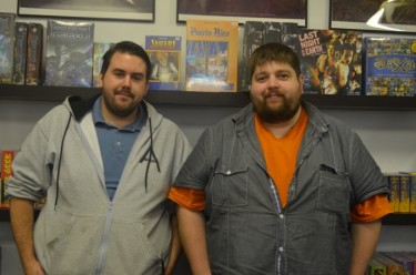 Joseph Allen and Greg Pothier pose in front of their board games.