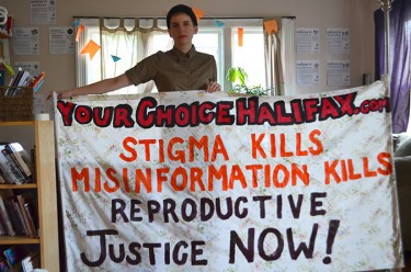 South House outreach coordinator poses with banner