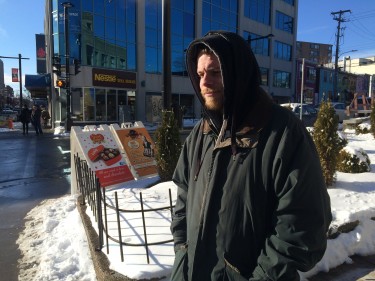 Man asks for spare change from passerby, across the street from the Halifax Central Library. Photo: Keili Bartlett
